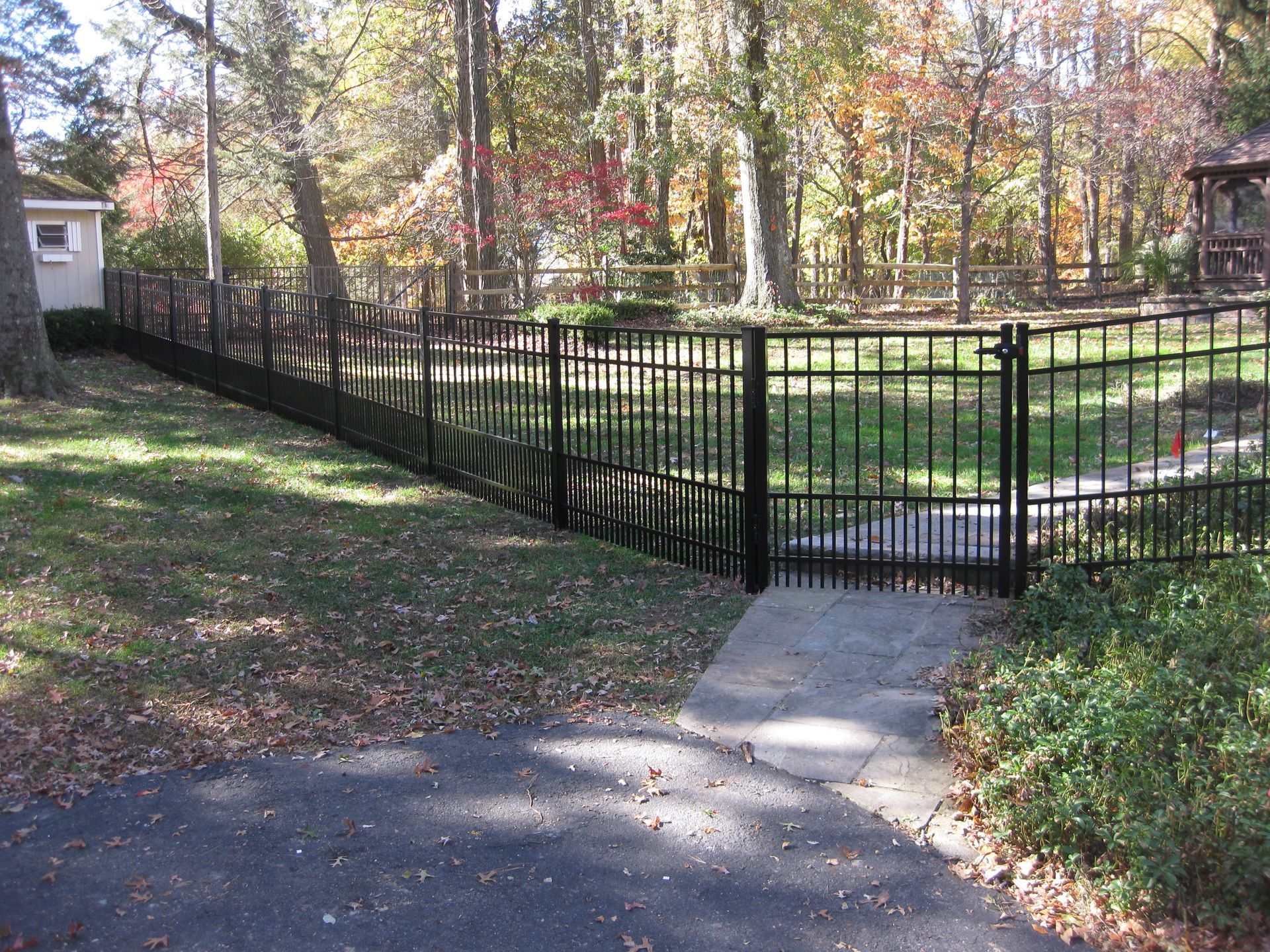 A black wrought iron fence surrounds a lush green yard.