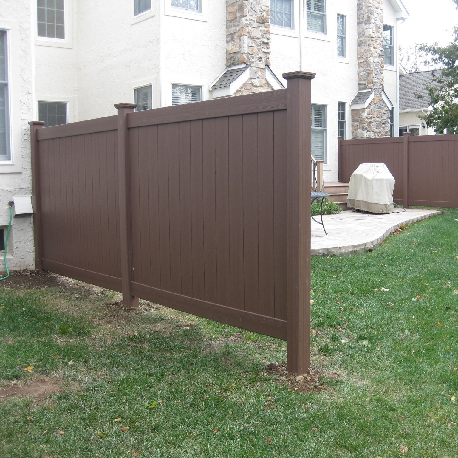 A brown fence surrounds the backyard of a house