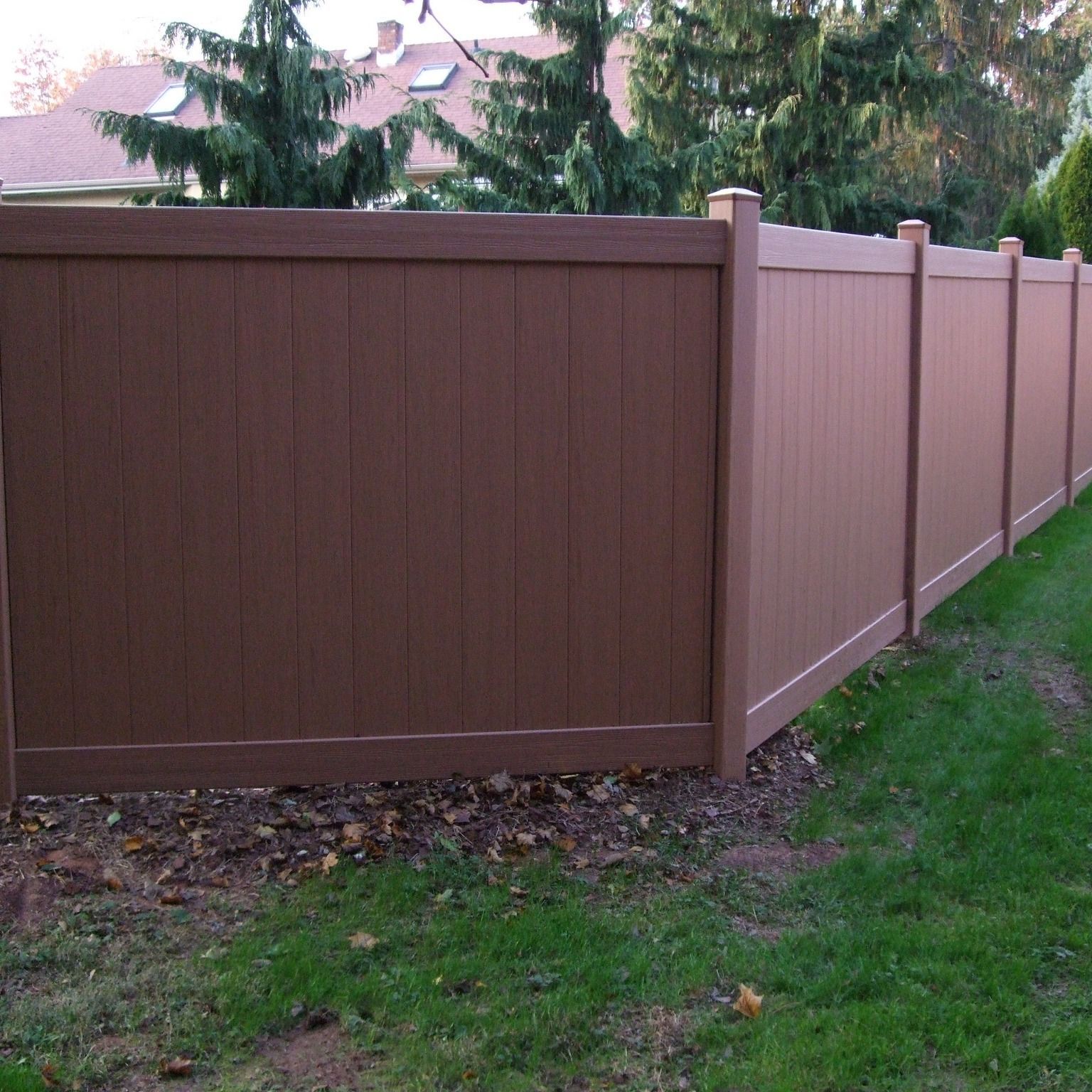 A brown wooden fence is surrounded by green grass