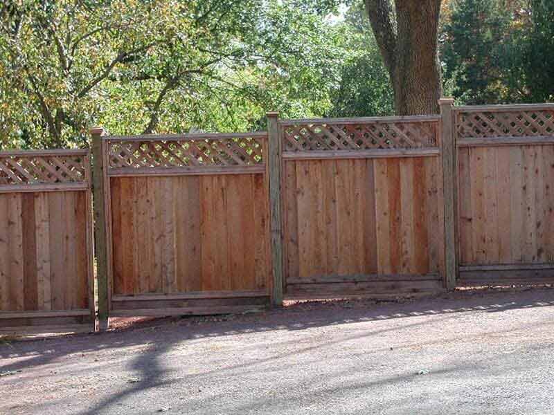 A wooden fence with a lattice design is surrounded by trees.