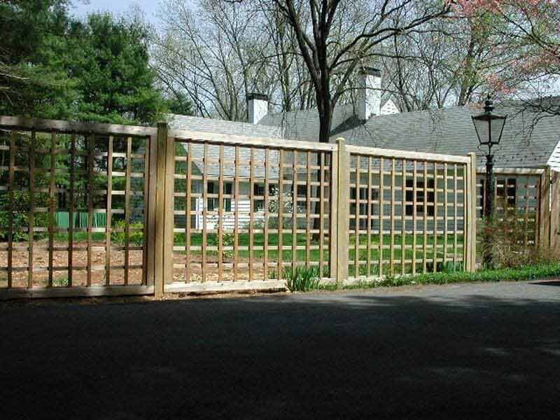 A wooden fence surrounds a driveway in front of a house