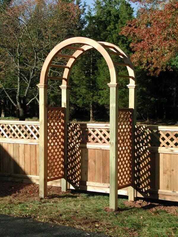A wooden arch is sitting in front of a wooden fence.