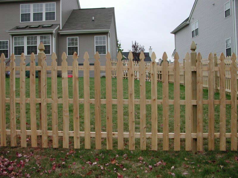 A wooden picket fence with a house in the background