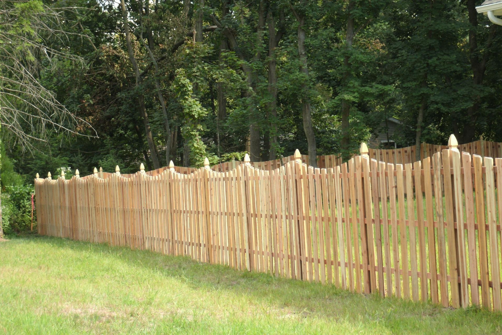 A wooden fence is sitting in the middle of a lush green field.