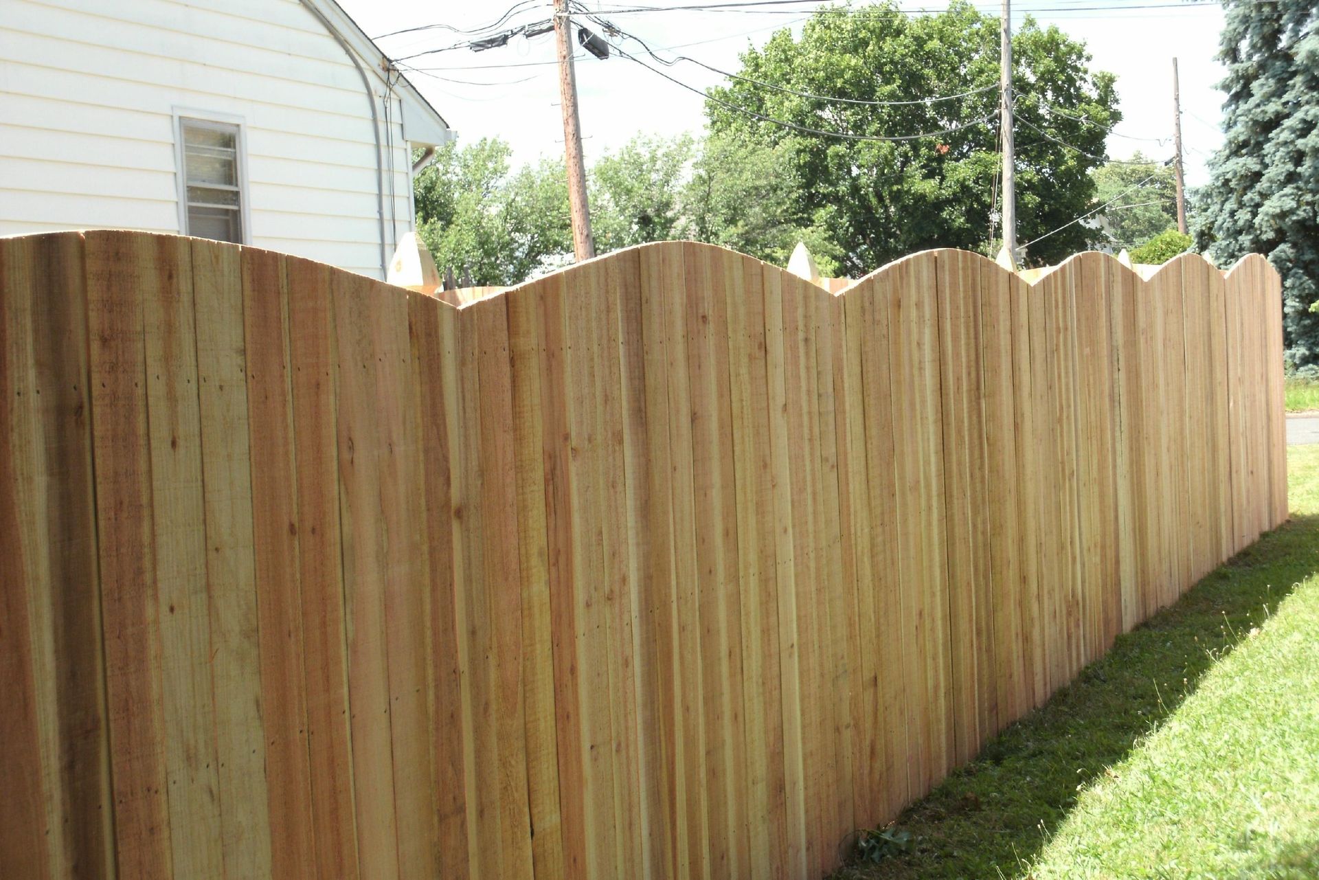 A wooden fence is sitting in the grass in front of a house.