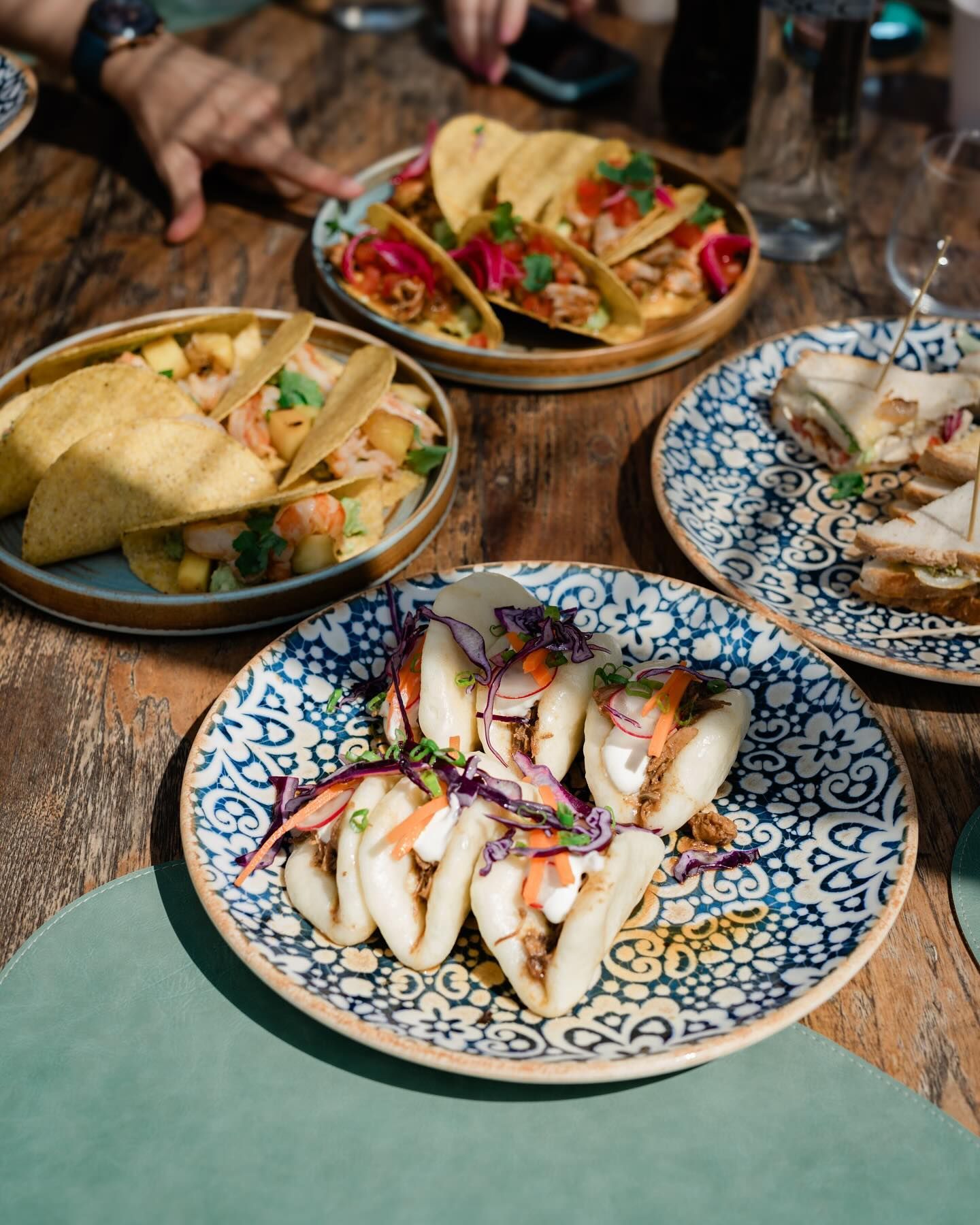 Un bicchiere di vino e una bottiglia su un tavolo. Il bicchiere è pieno di vino rosso. L'etichetta della bottiglia raffigura dei fiori blu.