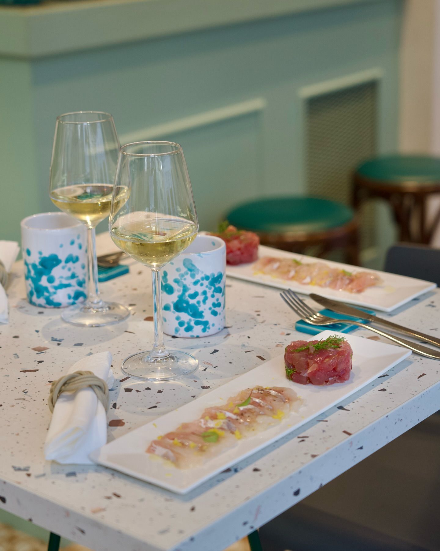 Piatto di frutti di mare con limoni e arance su un tavolo; bottiglie e bicchiere di vino sullo sfondo.