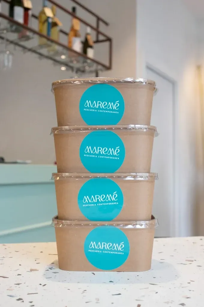 Pasta ai frutti di mare con gamberi, cozze, polpo, pomodori ed erbe aromatiche su un piatto bianco.