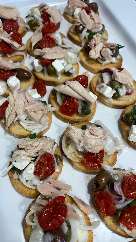 Piatto di frutti di mare con limoni e arance su un tavolo; bottiglie e bicchiere di vino sullo sfondo.