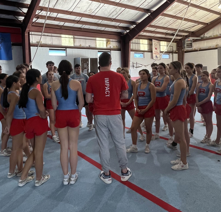 Athletes around their Choreographer recieiving instruction o