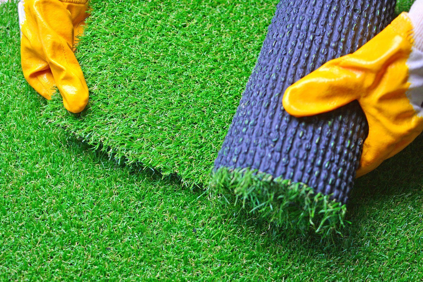A person is holding a roll of artificial grass in their hands.