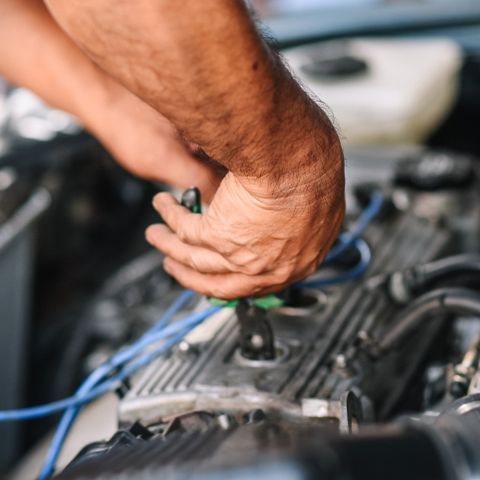 A Man Is Working On A Car Engine With A Pair Of Pliers — APPS Mechanical Port Macquarie In Port Macquarie, NSW