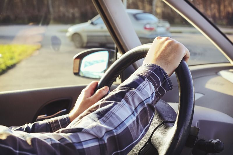 A Man In A Plaid Shirt Is Driving A Car — APPS Mechanical Port Macquarie In Port Macquarie, NSW