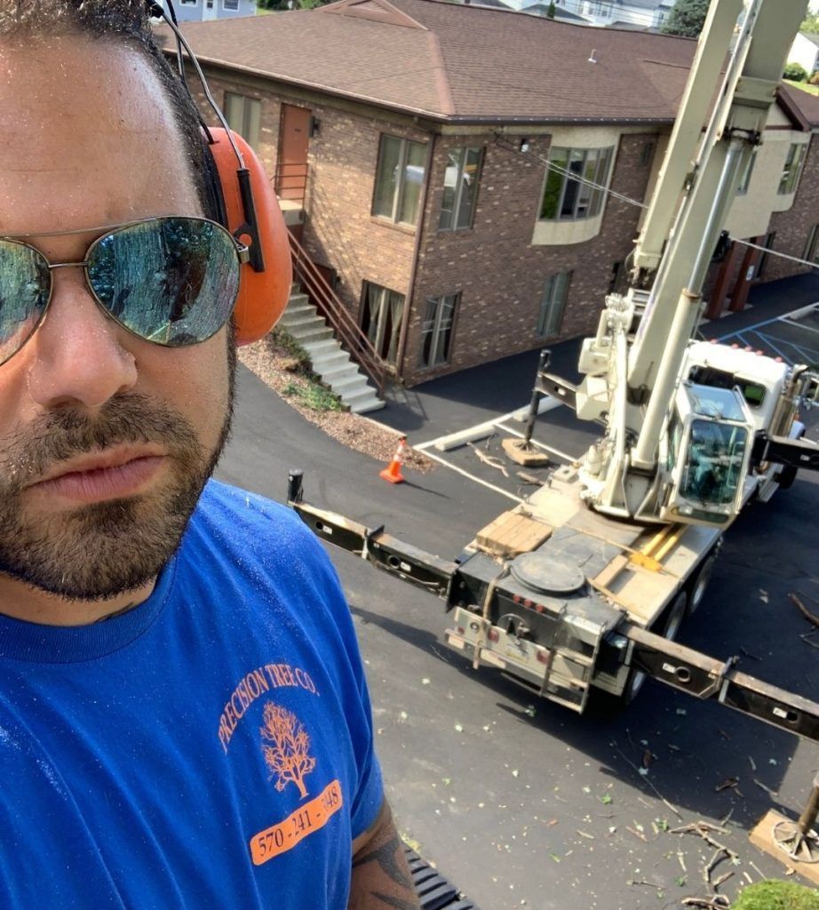 A man wearing sunglasses and ear muffs is standing in front of a crane
