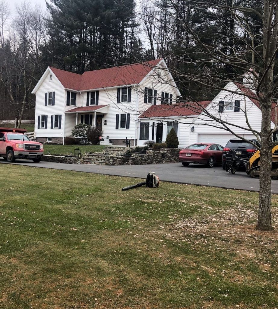 A large white house with a red roof and cars parked in front of it