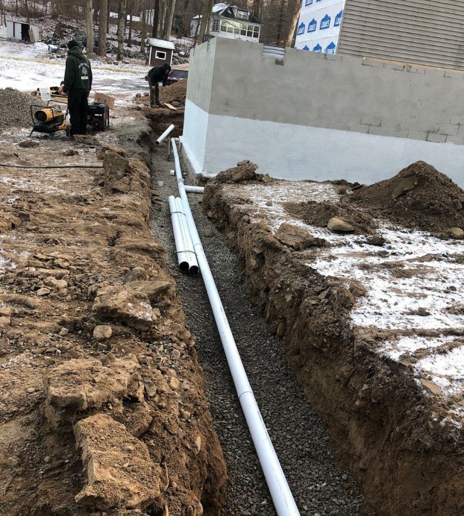 A man is working on a pipe in the dirt.