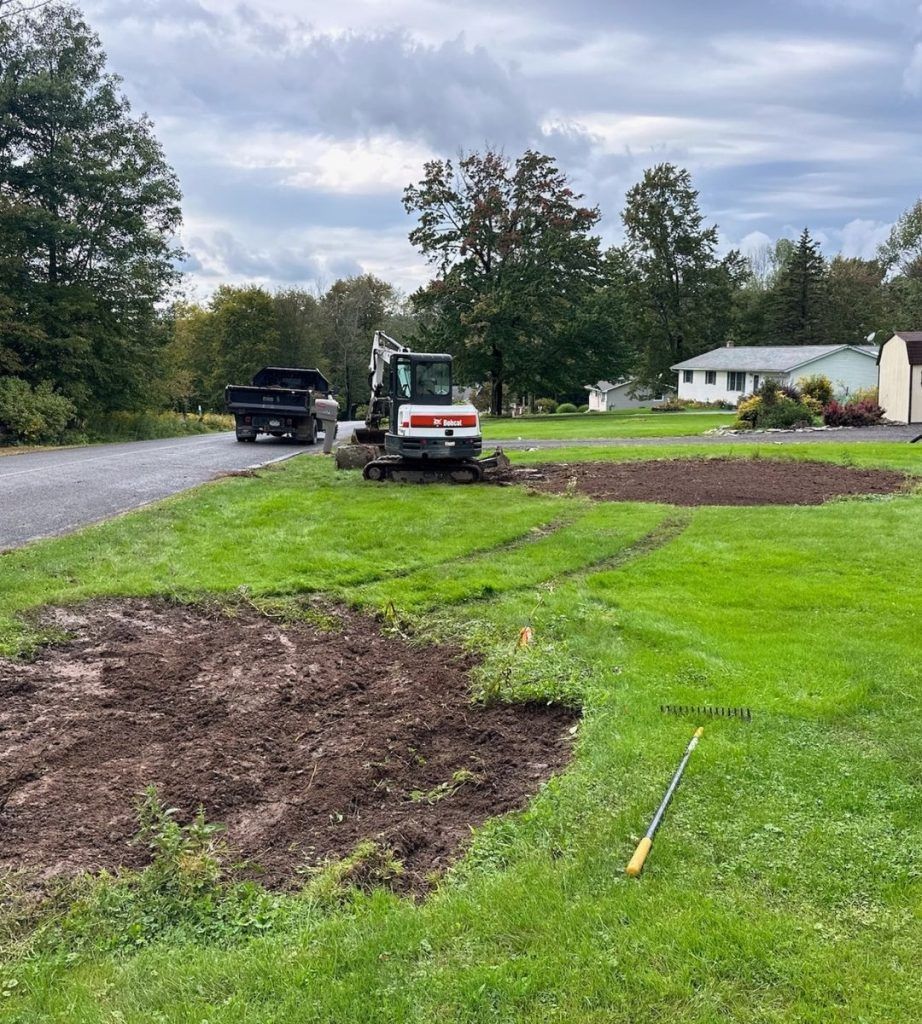 A bulldozer is digging a hole in the middle of a lush green field.