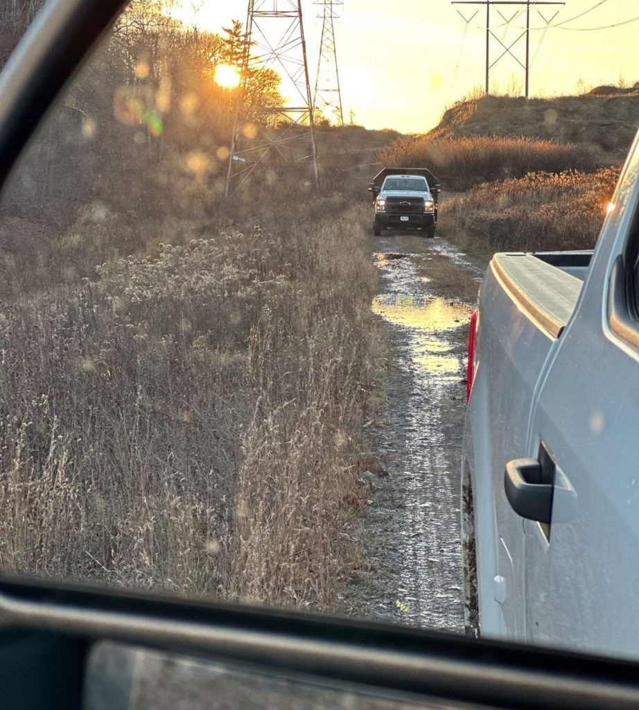 A truck is parked on the side of a dirt road