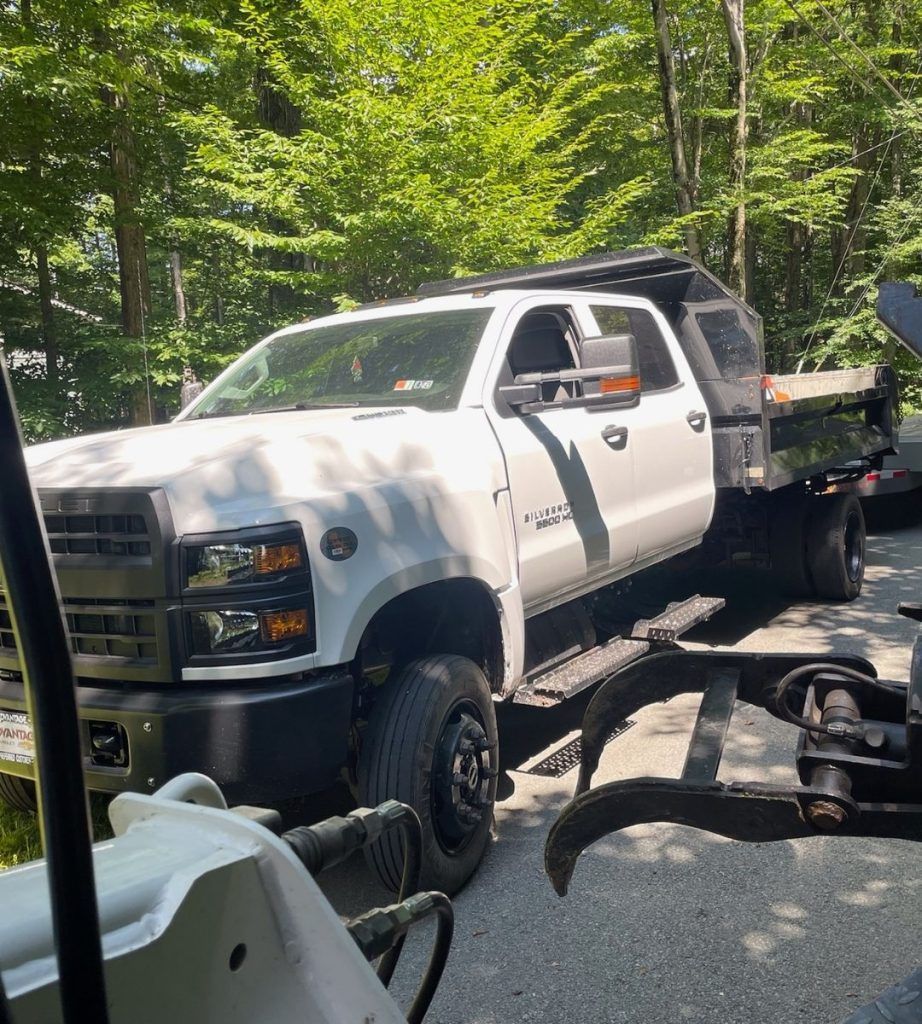A white truck is being towed by a tow truck