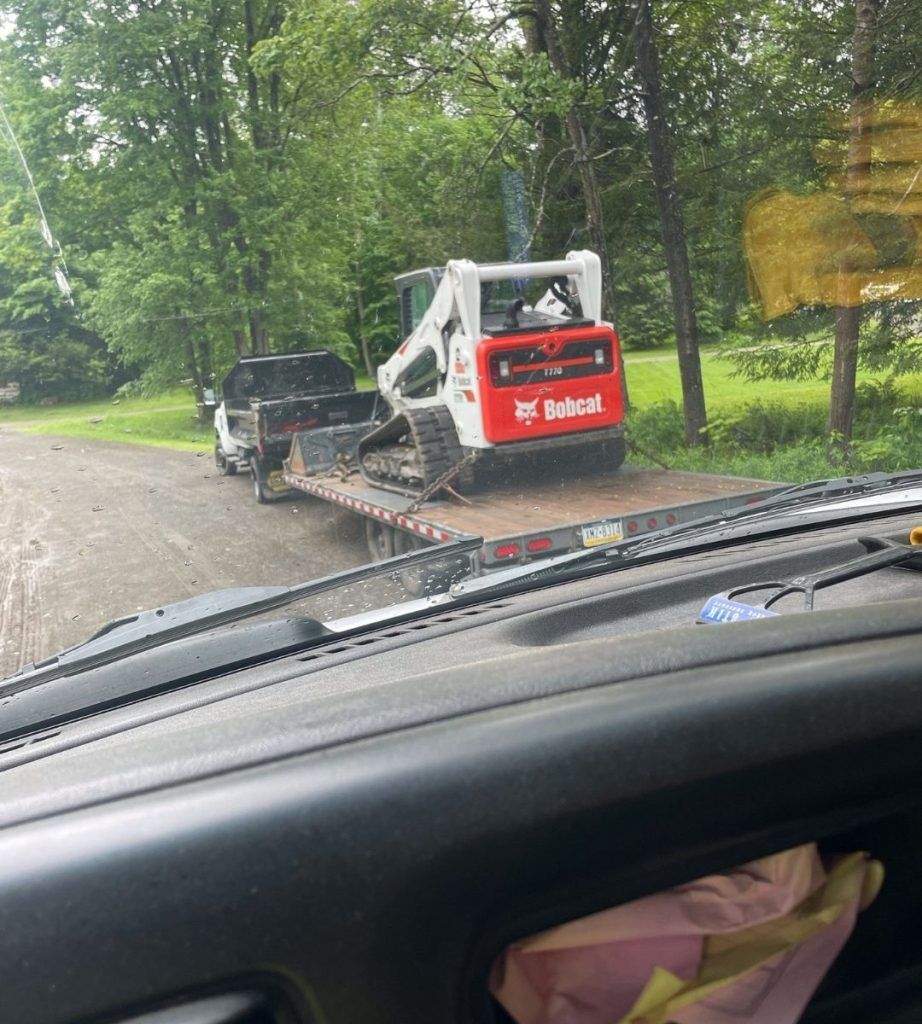 A bobcat tractor is sitting on top of a flatbed truck.