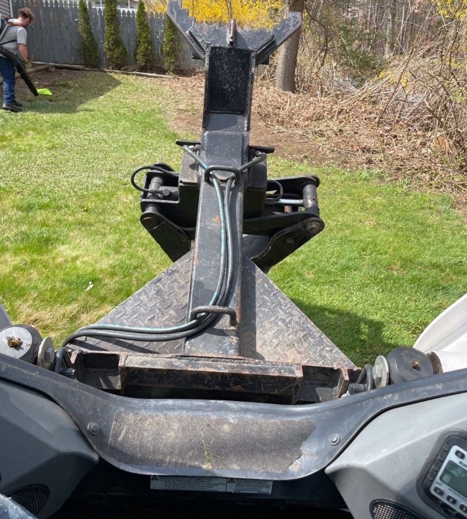 A man is blowing leaves from a lawn mower in a backyard