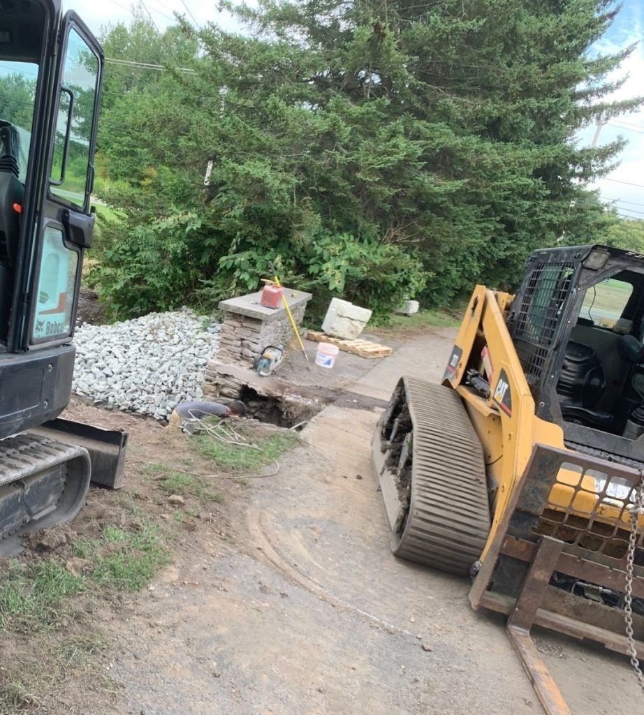 A bulldozer is driving down a dirt road next to a smaller bulldozer.