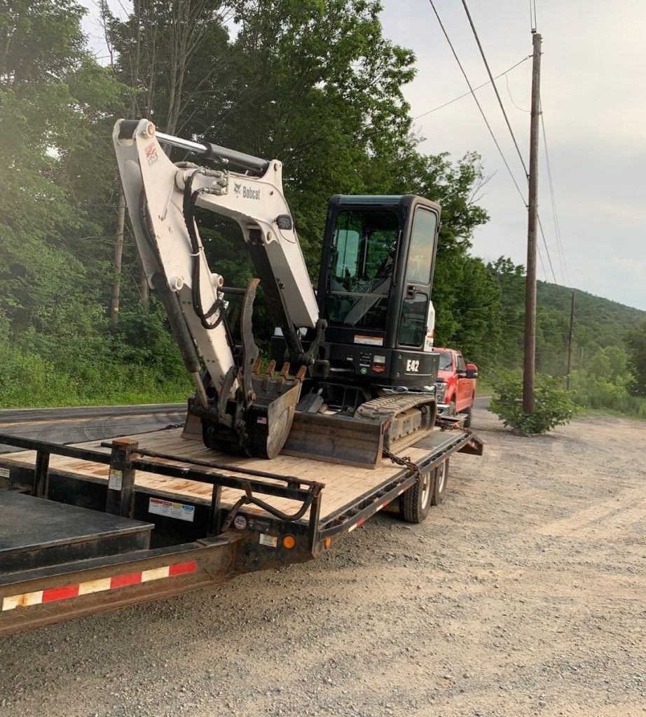 A bulldozer is sitting on top of a trailer on a dirt road.