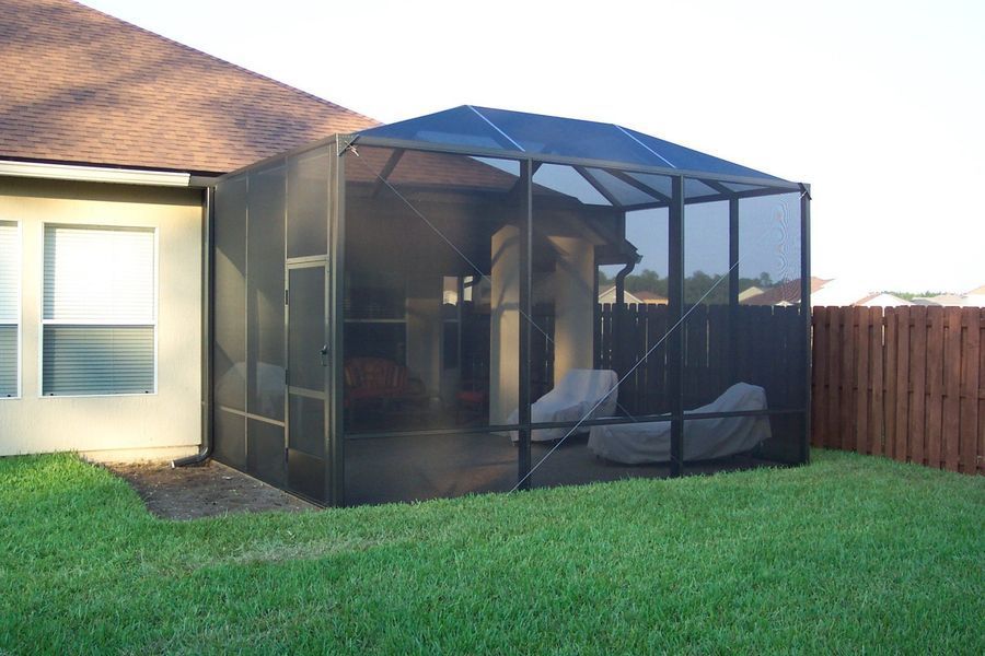 Screened-in patio attached to a house with black frame, dark screens, and two chairs inside.