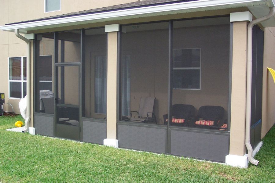 Screened porch with dark screens, beige pillars, and a grassy yard.