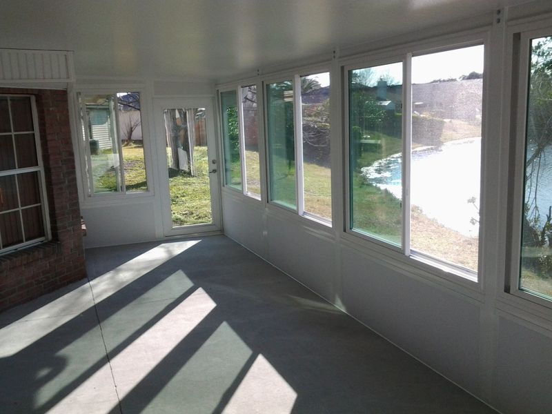 Sunroom with windows overlooking a backyard and pool; sunlight streams across the floor.