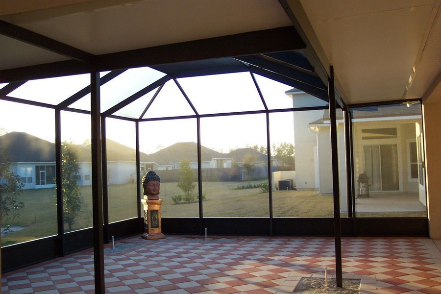 Screened patio with dark frame and tiled floor, overlooking a backyard with houses.