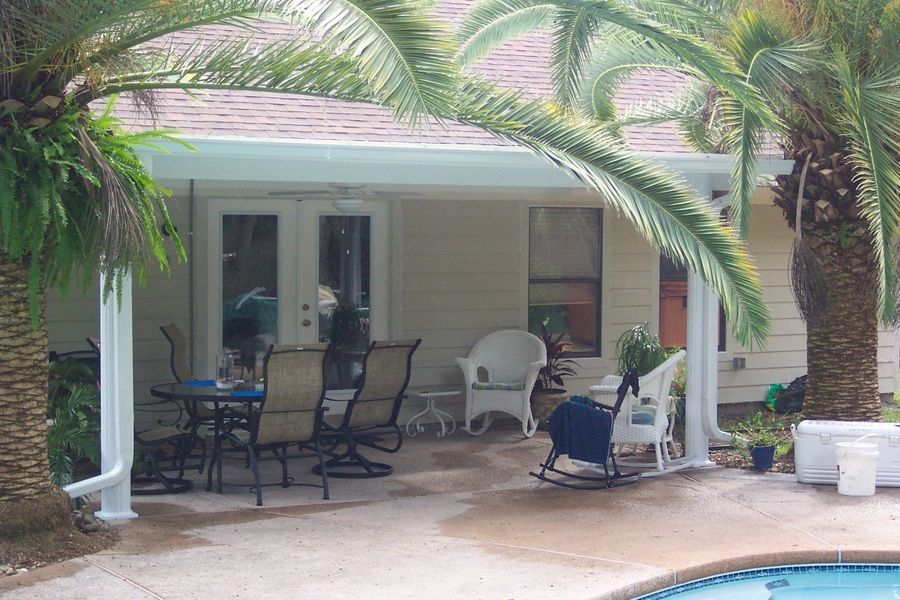 Patio with outdoor furniture, palm trees, and a pool.