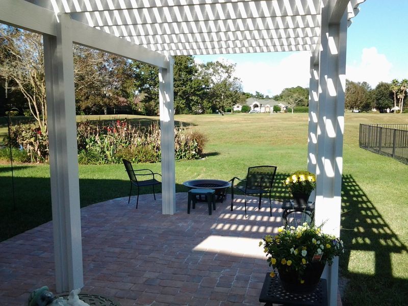 Patio with pergola, brick flooring, and outdoor furniture overlooking a grassy yard.