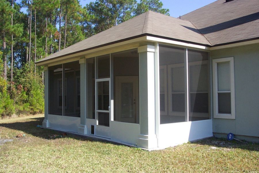 Screened-in porch attached to a house; white frame, gray screens, brown roof.
