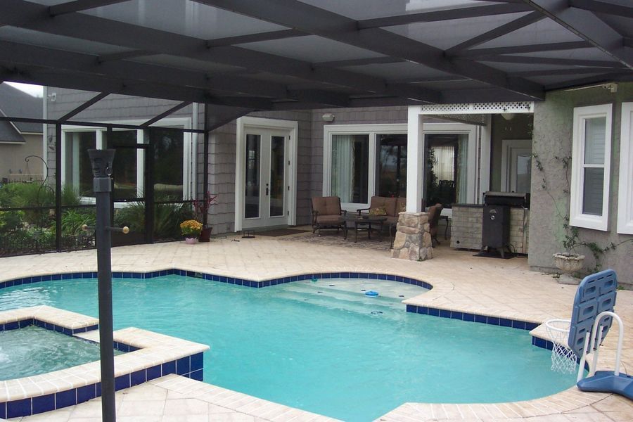 Pool and patio area with screened enclosure, pool, spa, and outdoor seating.
