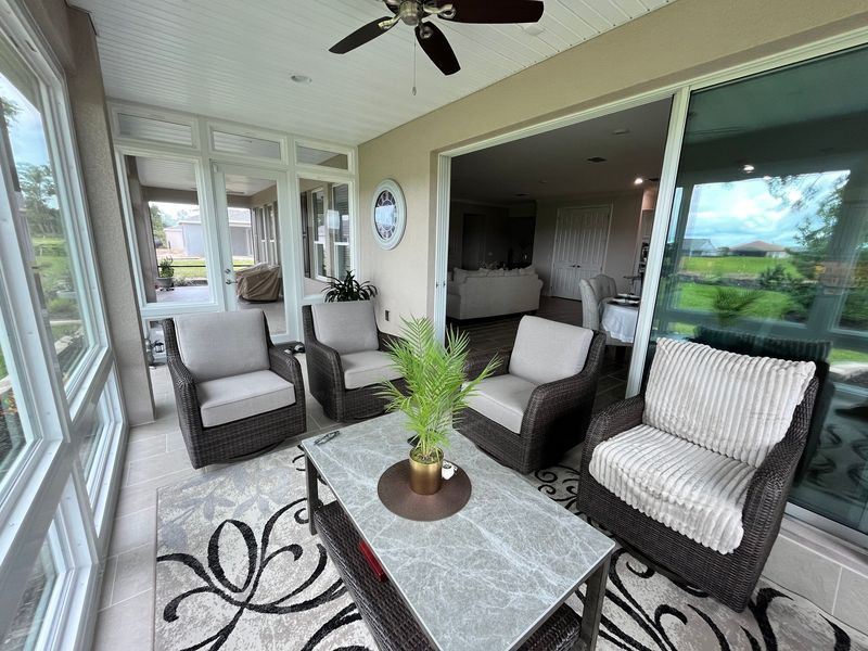 Sunroom with wicker furniture, a patterned rug, and a view of the outdoors.