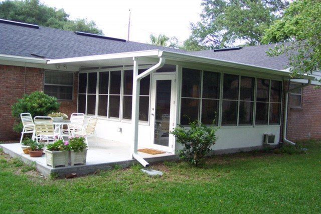 Screened-in patio with white frame, concrete patio, white door, and table with chairs.