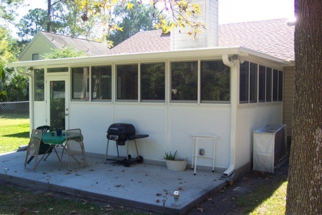 Screened-in porch attached to a house; white siding, concrete patio, grill, and air conditioning unit visible.
