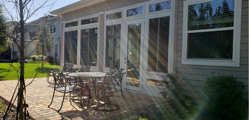 Patio with glass doors, table, chairs, and surrounding greenery.