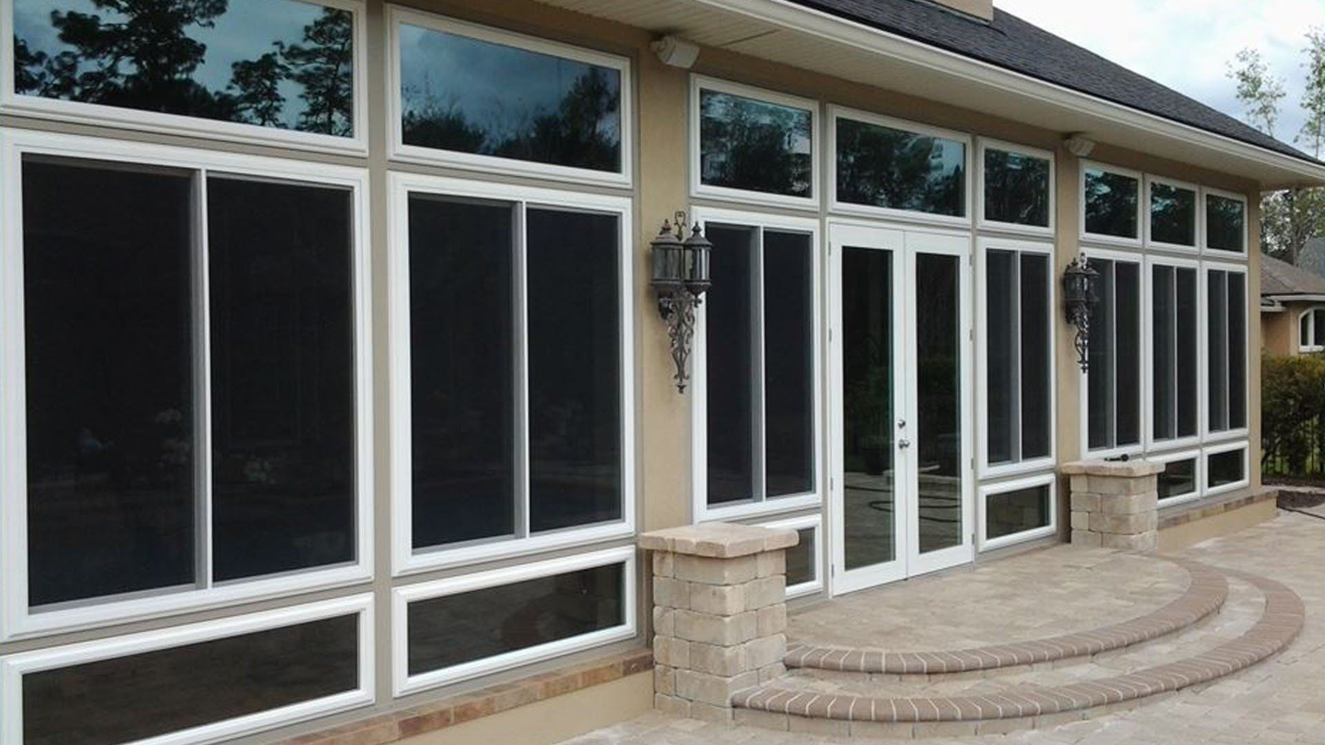 Sunroom with large windows, white frames, black screens, and a brick patio.