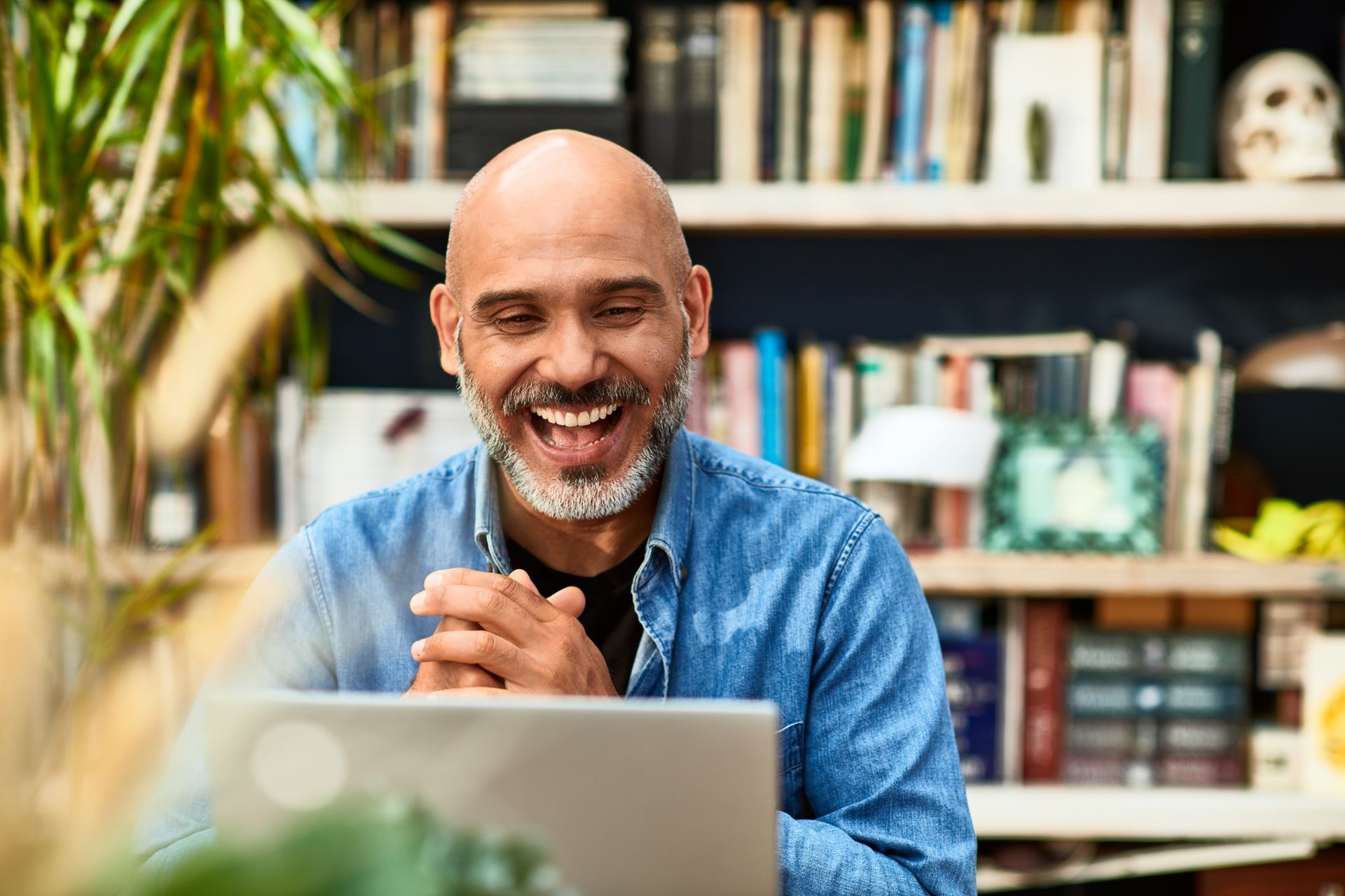A man is sitting in front of a laptop computer and smiling.