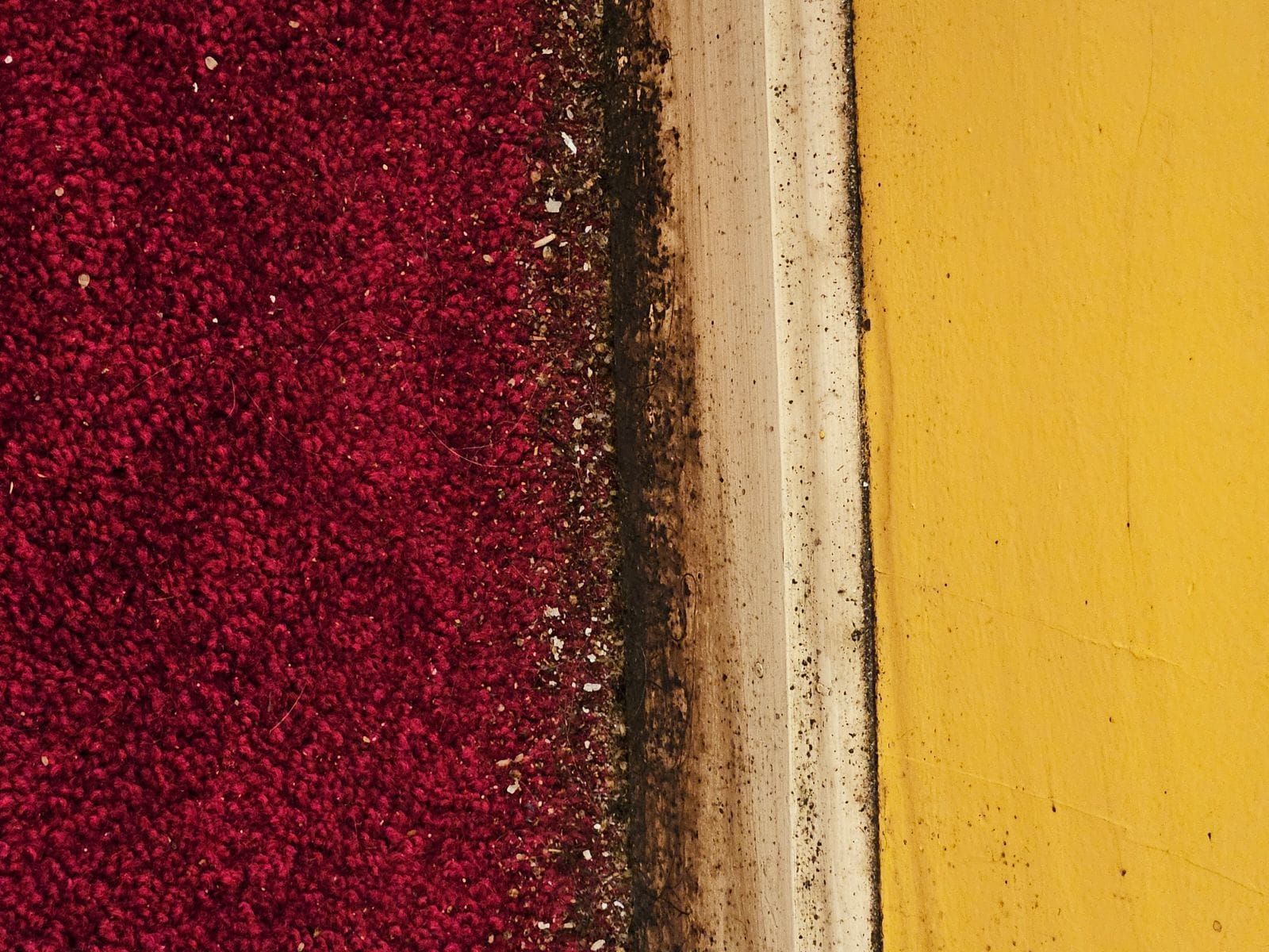 A close up of a red carpet next to a yellow wall.
