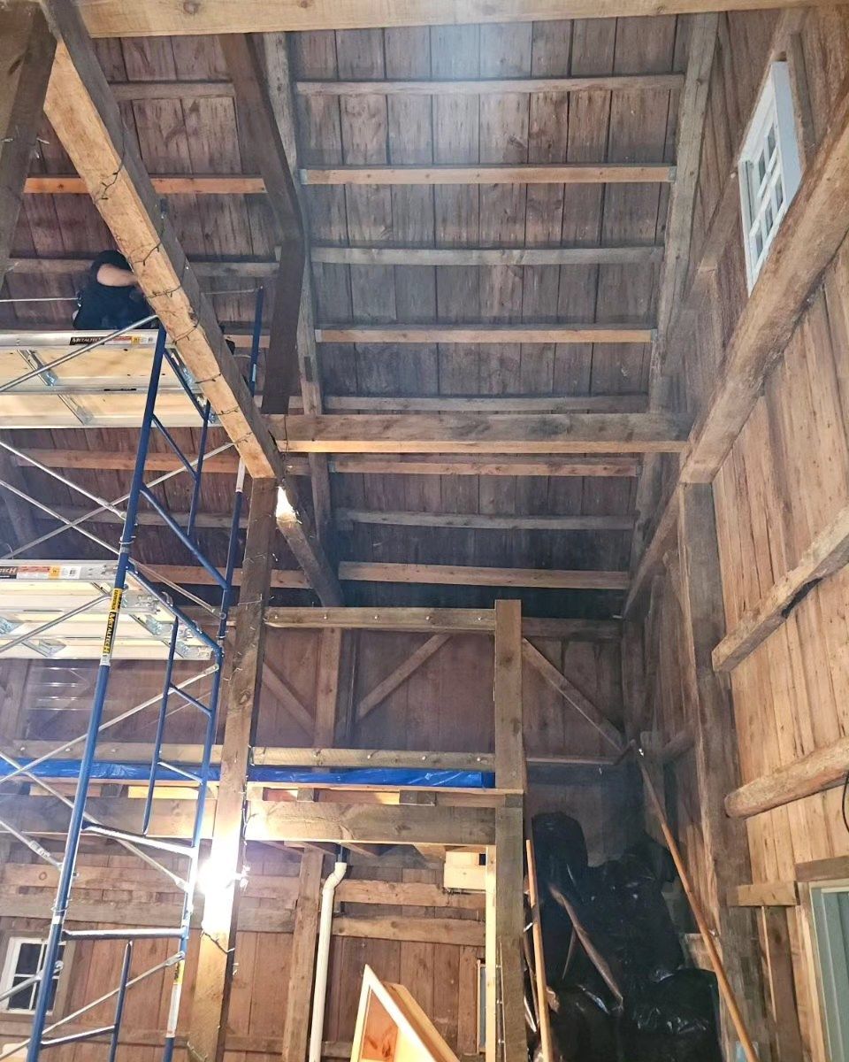 A man is working on a wooden structure with scaffolding