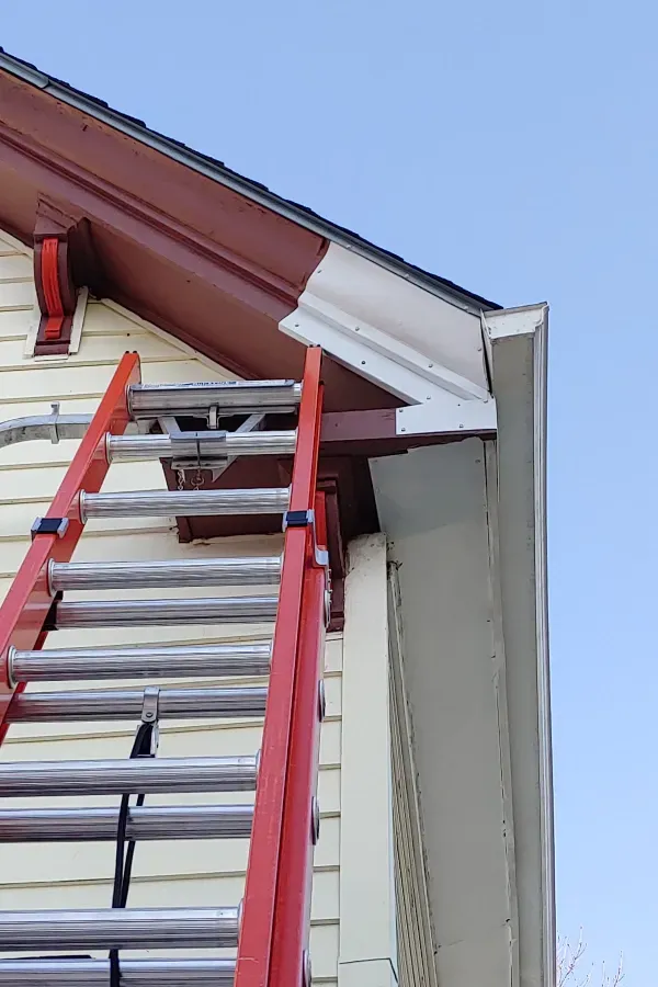 A red ladder is attached to the side of a house.