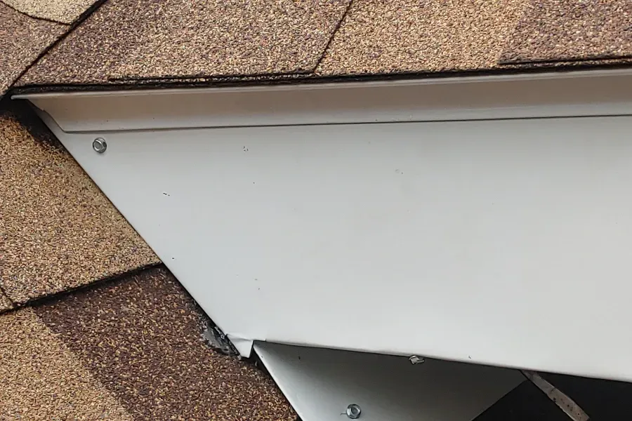 A close up of a roof with shingles and a white trim.