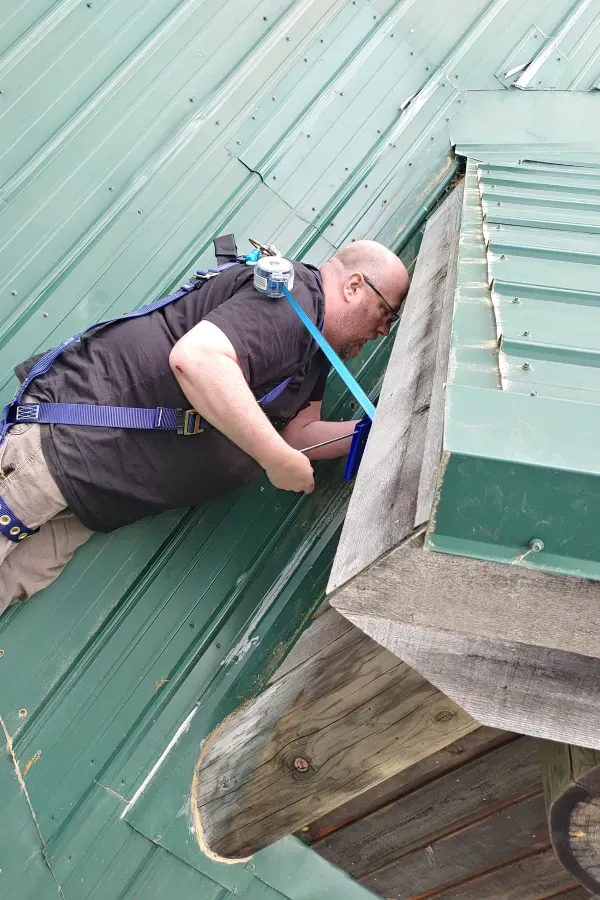A man is crawling on the roof of a building.