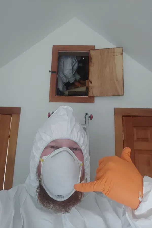 A man wearing a protective suit and mask is giving a thumbs up.