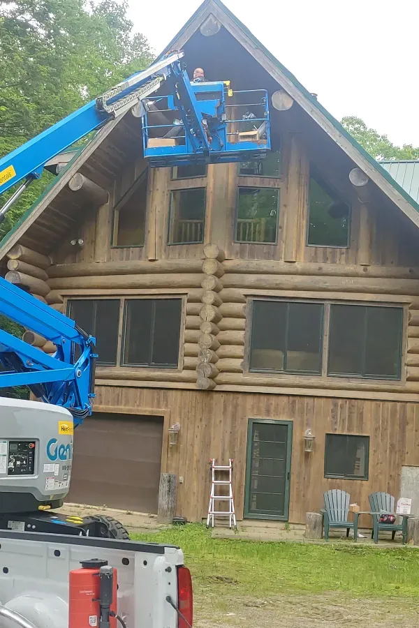 A large log cabin is being cleaned by a crane.