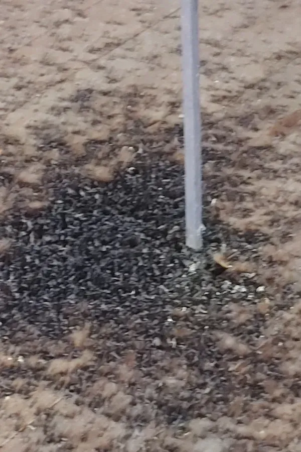 A white pole is sitting in the middle of a pile of gravel.