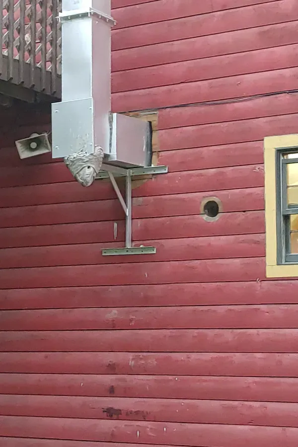 A red wooden building with a ventilation system attached to it.